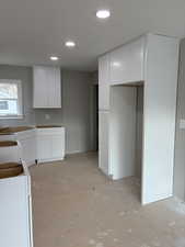 Kitchen with white cabinetry, Pantry recessed lighting, and concrete floors