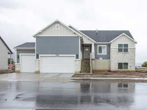 View of front facade with stone siding, board and batten siding, driveway, and a shingled roof