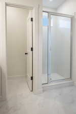 Bathroom with light marble finish flooring and a shower stall