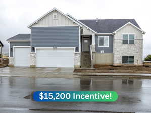Craftsman-style house with stone siding, board and batten siding, and concrete driveway