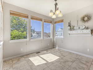 Unfurnished dining area featuring a chandelier and light tile patterned floors