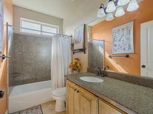 Full bath with shower / bath combination with curtain, vanity, and light tile patterned floors