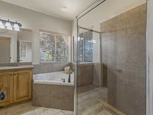 Bathroom featuring vanity, a stall shower, a garden tub, and light tile patterned floors