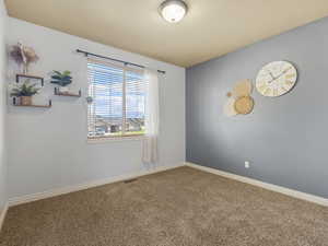 Carpeted spare room featuring baseboards