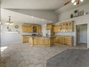 Kitchen featuring light tile patterned floors, an island with sink, recessed lighting, vaulted ceiling, and stainless steel appliances
