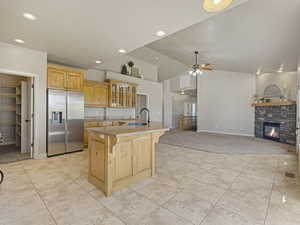 Kitchen with stainless steel fridge, glass insert cabinets, a fireplace, a breakfast bar, and light brown cabinetry