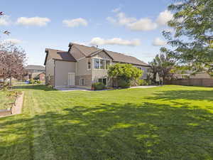 Back of house featuring board and batten siding, stone siding, and a patio