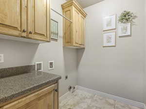 Washroom with light tile patterned floors, hookup for a washing machine, electric dryer hookup, and cabinet space