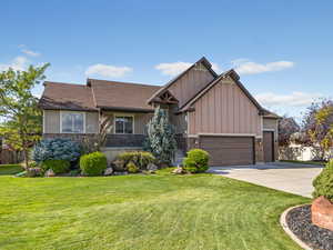 Craftsman house with board and batten siding, stone siding, a front yard, concrete driveway, and a porch