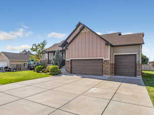 Craftsman-style house with driveway, board and batten siding, a garage, a front lawn, and stone siding