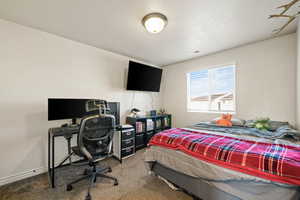 Carpeted bedroom featuring a textured ceiling and an office area