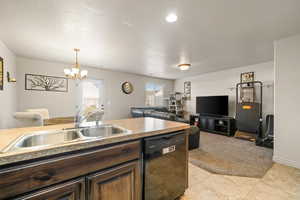 Kitchen featuring dishwasher, dark brown cabinetry, pendant lighting, a chandelier, and open floor plan