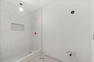 Basement full bath with a tile shower and tile patterned floors