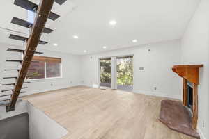 Unfurnished living room with stairway, light wood finished floors, a fireplace, and recessed lighting