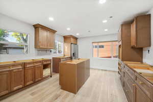 Remodeled Kitchen (1st floor) featuring brown cabinets, recessed lighting, light wood finished floors, a center island, and stainless steel fridge - pick your own counter tops!