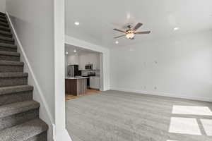 Unfurnished living room with stairs, light colored carpet, recessed lighting, and ceiling fan