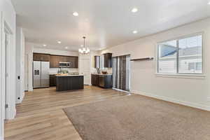 Kitchen with light countertops, stainless steel appliances, a chandelier, recessed lighting, and dark brown cabinets