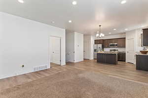 Kitchen featuring open floor plan, hanging light fixtures, recessed lighting, dark brown cabinets, and a chandelier