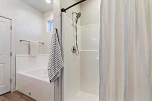 Bathroom featuring a shower stall, a garden tub, and wood finished floors