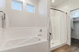 Bathroom featuring a shower stall, a garden tub, and wood finished floors