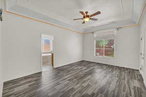 Empty room featuring a raised ceiling, wood finished floors, and ceiling fan