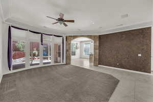 Unfurnished room with light tile patterned floors, a chandelier, arched walkways, and a ceiling fan