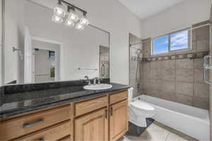 Bathroom featuring washtub / shower combination, vanity, and light tile patterned floors