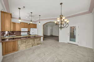 Kitchen featuring dark countertops, a peninsula, tasteful backsplash, brown cabinets, and white appliances