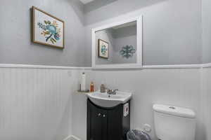 Bathroom featuring vanity, wainscoting, and a textured wall
