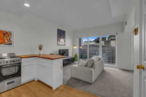 Living area with recessed lighting, light carpet, and light wood-style flooring