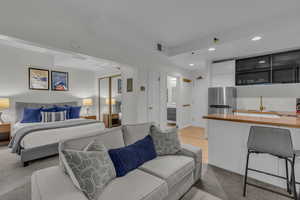 Bedroom featuring recessed lighting, freestanding refrigerator, a closet, light wood-type flooring, and light carpet