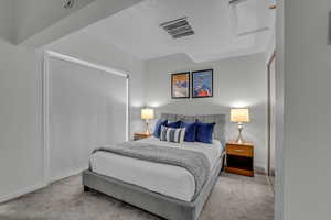 Carpeted bedroom featuring a closet and attic access