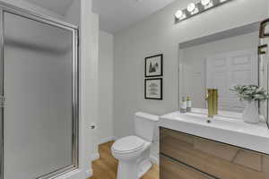 Bathroom featuring a shower stall, vanity, and light wood finished floors