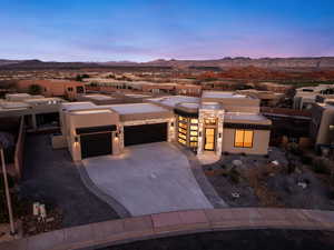View of front of house featuring a garage, driveway, stucco siding, and a patio