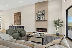 Living room with light wood finished floors, recessed lighting, and a glass covered fireplace