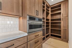 Kitchen with stainless steel oven, light wood-style flooring, and light stone countertops
