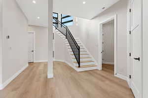 Staircase with wood finished floors and recessed lighting