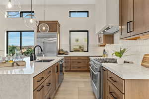 Kitchen with light stone counters, premium appliances, and wood finish cabinets