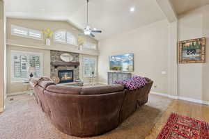 Living room with high vaulted ceiling, a ceiling fan, and a stone fireplace