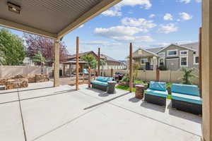 Fenced backyard with an outdoor living space with a fire pit, a gazebo, a patio area, a residential view, and area for grilling