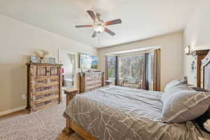 Carpeted bedroom featuring ceiling fan and ensuite bathroom