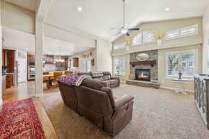 Living room featuring high vaulted ceiling, a fireplace, a ceiling fan, light carpet, and recessed lighting