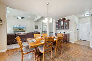 Dining space featuring light wood-style floors, a chandelier, and a ceiling fan