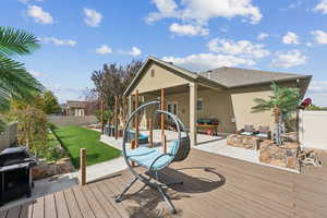 Wooden terrace with a fenced backyard, a patio area, and a grill
