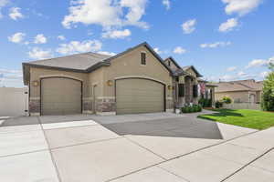 View of front of home featuring an attached garage, stucco siding, concrete driveway, and brick siding