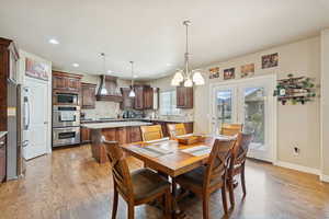 Dining space with light wood-style flooring, french doors, recessed lighting, and a chandelier