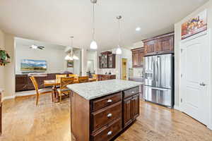Kitchen featuring stainless steel fridge, open floor plan, a chandelier, a center island, and hanging light fixtures