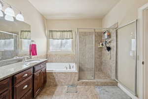 Full bath with vanity, a shower stall, a bath, and light tile patterned floors