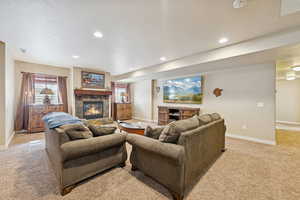Living area with a tile fireplace, light carpet, and recessed lighting
