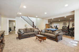 Living room featuring light colored carpet, recessed lighting, and stairway